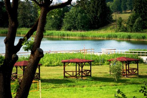 three picnic tables in a field next to a lake at Jaskółka - pokoje i apartament przy plaży in Olsztyn