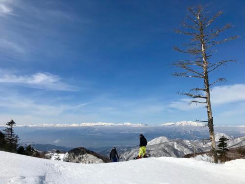 two people standing on top of a snow covered mountain at Okushiga Lodge Yama no Manimani in Yamanouchi