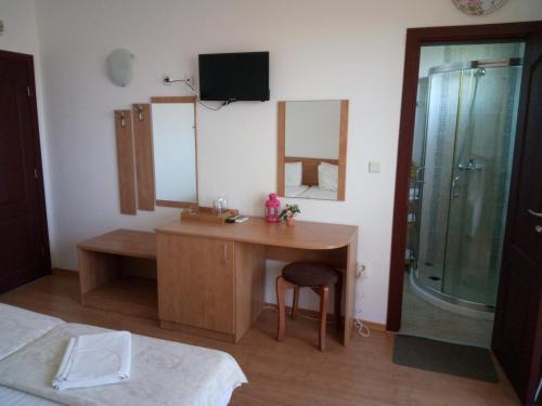 a bedroom with a desk and a shower with a mirror at Family Hotel Bellehouse in Chernomorets