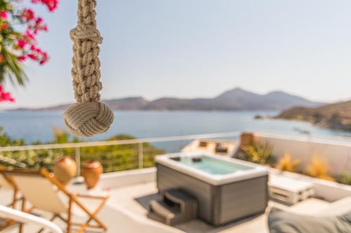 a balcony with a hot tub and chairs and the water at Villa SOLEIL in Adamas