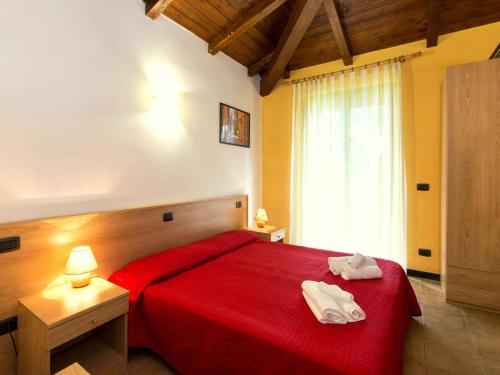 una camera da letto con un letto rosso con due asciugamani di Cozy Holiday Home with Swimming Pool near Lake in Liguria a Bolano