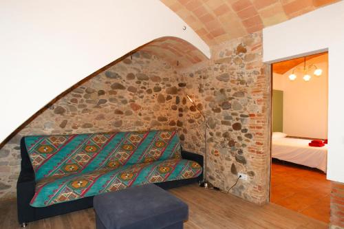 un soggiorno con divano e parete in pietra di Can Quel dels Alls - Best friendly a Celrá