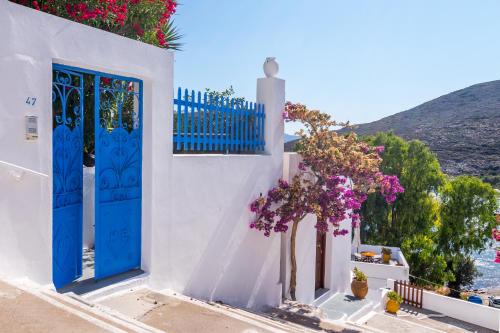 a white building with blue doors and flowers at Villa SOLEIL in Adamas