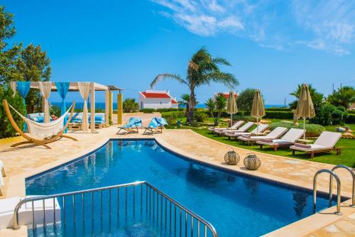 a swimming pool with chairs and umbrellas in a resort at Azzuro Villa with private pool by Estia in Hersonissos