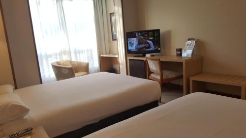 a hotel room with two beds and a television at Senator Barajas in Madrid