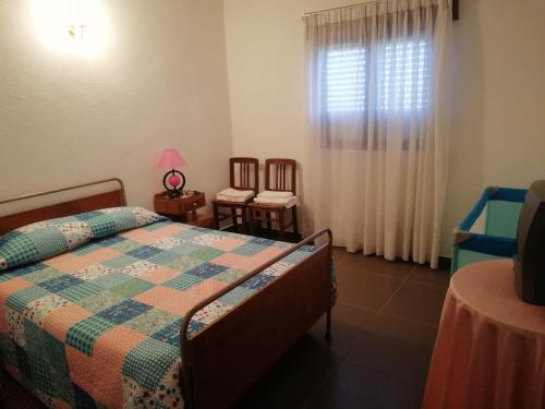 a bedroom with a bed and two chairs and a window at Residencial Ponto Certo in Vilar Torpim