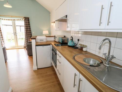 a kitchen with white cabinets and a sink at The Button Box in Huddersfield
