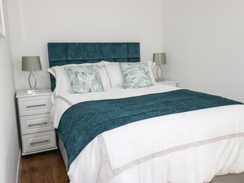 a bedroom with a large bed with a blue headboard at 6 Mill Wharf in Berwick-Upon-Tweed