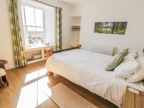Un dormitorio con una gran cama blanca y una ventana en Corrafeckloch Forest Cottages en Bargrennan