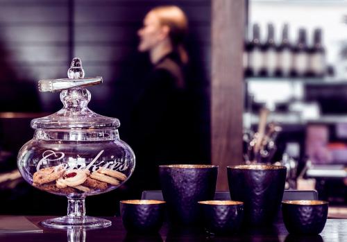 a glass jar with cookies in it on a table with cups at Arctic City Hotel in Rovaniemi