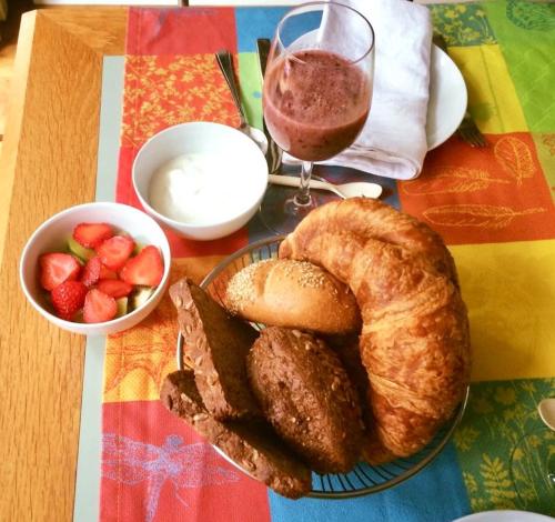 a table with a plate of bread and a bowl of strawberries at Bed&Brood Comon in Ubbergen