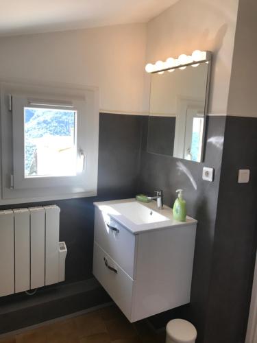 een badkamer met een witte wastafel en een spiegel bij Lavande 3ème étage in Le Mas