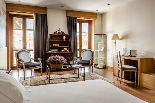 a bedroom with a bed and two chairs and a desk at Gran Hotel La Perla in Pamplona