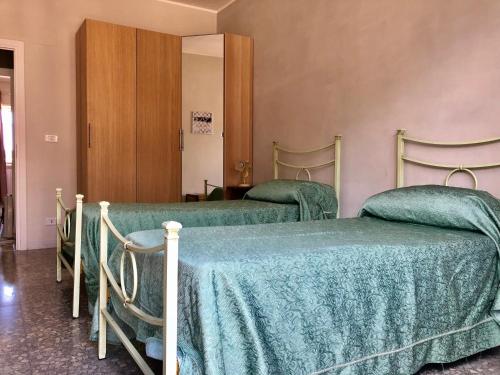 two beds with green covers in a room at Casa vacanze in Terracina