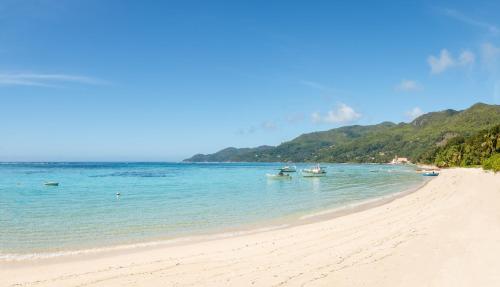 a sandy beach with boats in the water at Shanaz Beachside Retreat in Anse Royale
