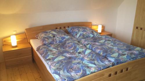 ein Bett mit blauer Decke und zwei Nachttischen in der Unterkunft Das Burgberghaus Apartment Talaue 1.OG in Bergstein