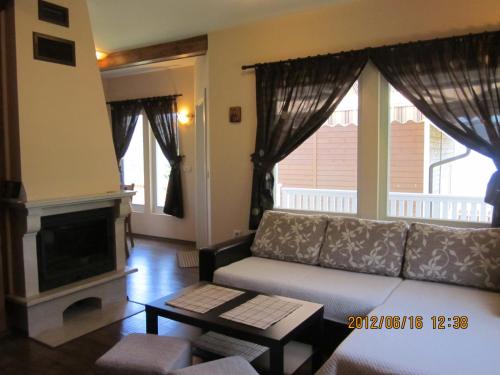 een woonkamer met een bank en een open haard bij Holiday Village Orlino in Sarnitsa