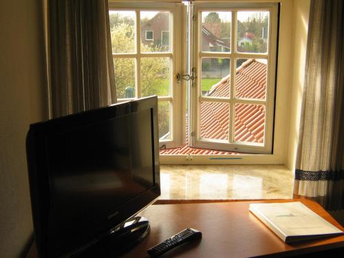 a television sitting on a table in front of a window at Hotel Friesische Wehde in Bockhorn