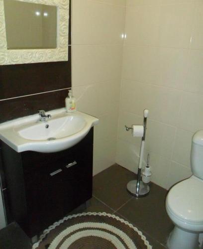 a bathroom with a sink and a toilet and a mirror at Residencial Ponto Certo in Vilar Torpim