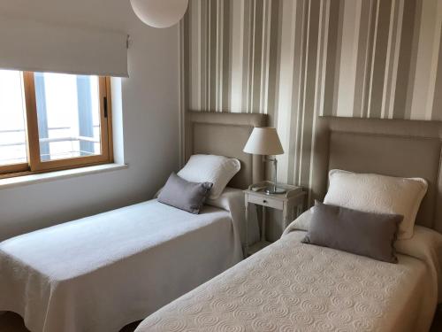 セジンブラにあるApartamentos de Lujo con vistas al Marのベッド2台と窓が備わるホテルルームです。