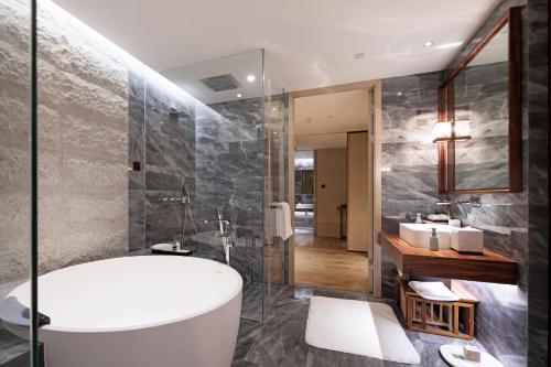 a bathroom with a bath tub and a sink at The Anandi Hotel and SPA - Luxury Healing Hotel for Wellbeing in Shanghai