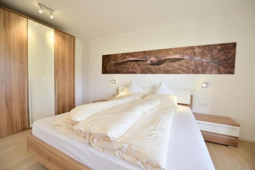 uma cama branca com lençóis e almofadas brancos em Appartment Silvia in St Andrä bei Brixen em Bressanone