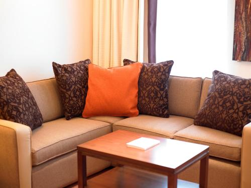 a living room with a couch with pillows and a table at Best Western Plus Milford Hotel in South Milford