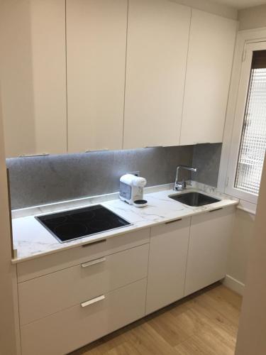una cocina con armarios blancos y fregadero en Apartamento Tiboli con parking gratuito en Bilbao