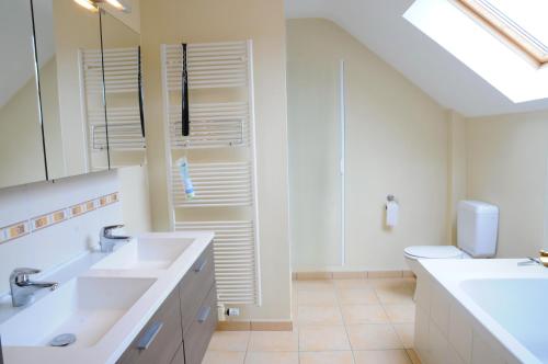 a white bathroom with two sinks and a toilet at Villa Bardot in Durbuy
