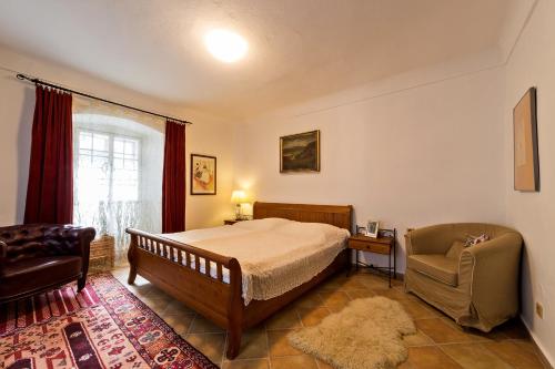 um quarto com uma cama, uma cadeira e uma janela em Pension Cortes em Český Krumlov