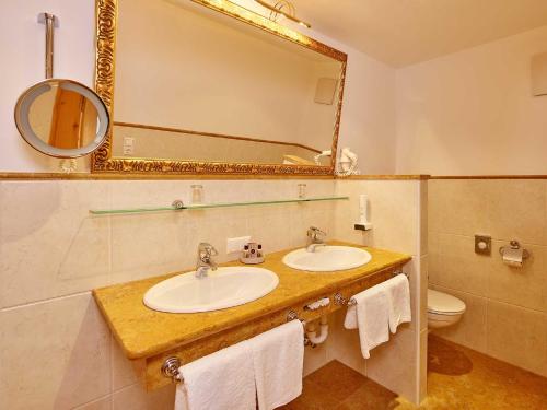 a bathroom with two sinks and a mirror and a toilet at Hotel Sonnhof in Neustift im Stubaital
