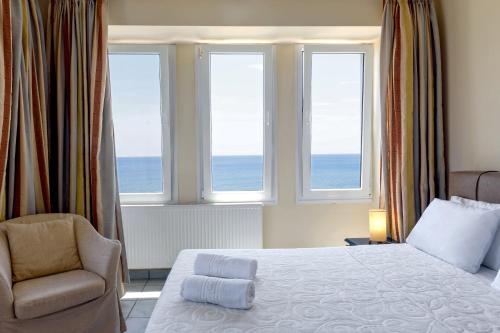 a bedroom with a bed and a chair and windows at Sea Breeze Apartments Chios in Monolia