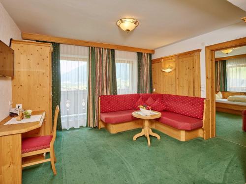 a living room with a red couch and a table at Hotel Sonnhof in Neustift im Stubaital