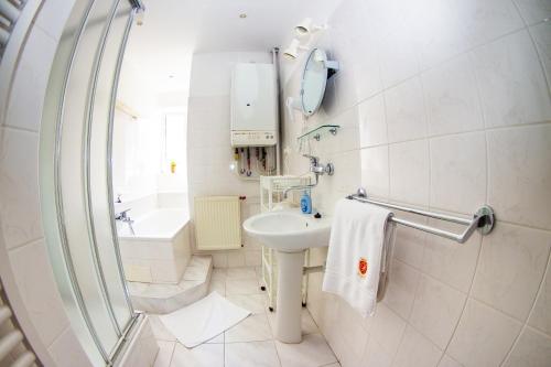 ein weißes Badezimmer mit einem Waschbecken und einer Badewanne in der Unterkunft Apartmán U krále Komenského in Jičín