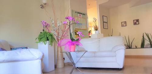 een woonkamer met een witte bank en een tafel met paarse bloemen bij Hotel Provenza in Ventimiglia