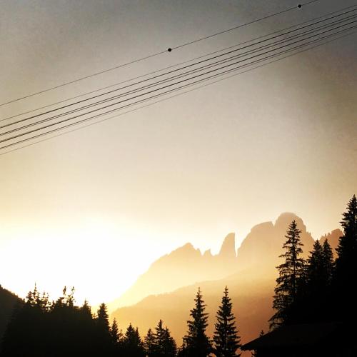 a view of the mountains at sunset at Hotel Villa Rosella Park & Wellness in Canazei