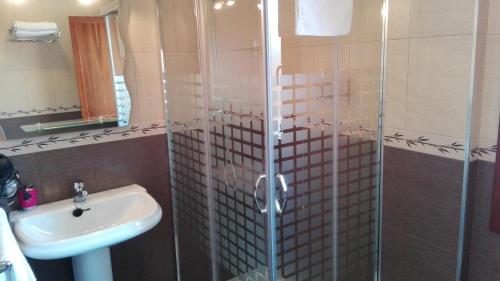 a bathroom with a sink and a glass shower at Apartamentos Las Rosas in Cue