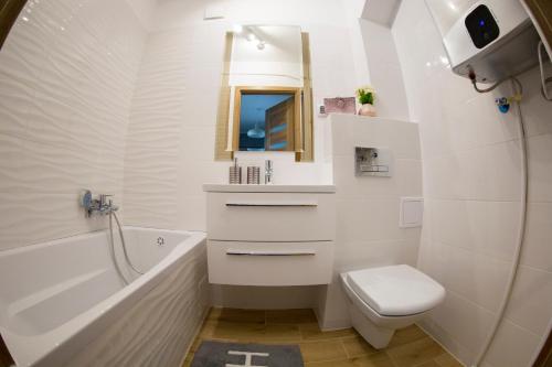 a bathroom with a toilet and a tub and a sink at Apartament Centrum in Lidzbark Warmiński
