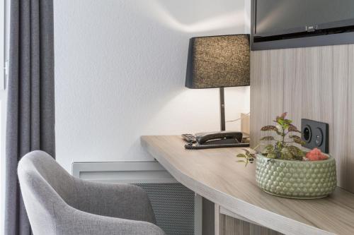 a room with a desk with a lamp and a chair at Nemea Appart Hotel Stadium Bordeaux aéroport in Mérignac