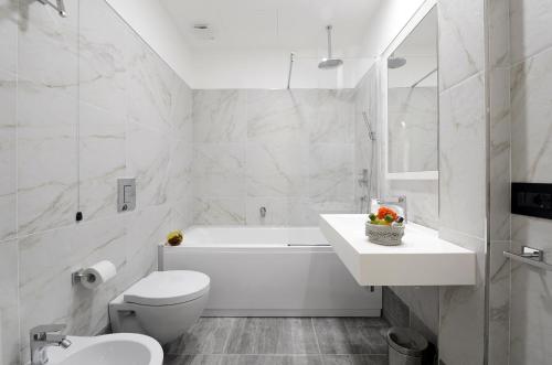 a white bathroom with a tub and a toilet and a sink at Best Western Hotel Principe di Lampedusa in Palermo