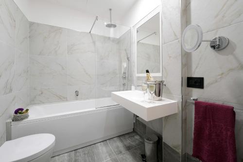 a white bathroom with a sink and a tub and a toilet at Best Western Hotel Principe di Lampedusa in Palermo