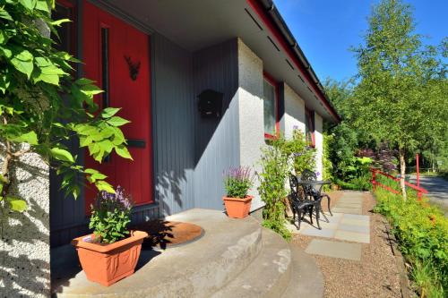 a house with a red door and some plants at The Bridge Suite in Invermoriston