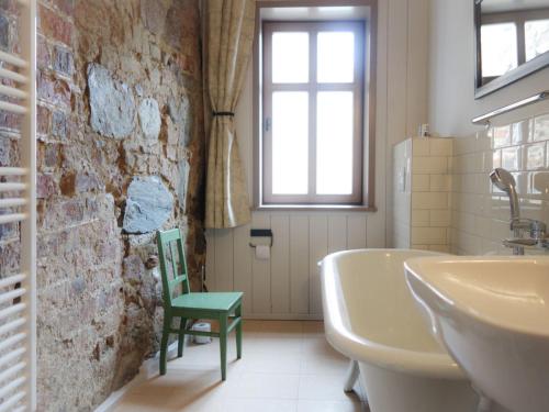 a bathroom with a bath tub and a green chair at Schrot-Kontor in Tangermünde
