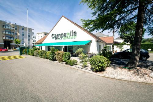 a building with a sign on the side of a street at Campanile Genève - Ferney-Voltaire in Ferney-Voltaire