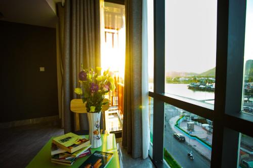 a vase of flowers on a table next to a window at Moonlight Bay Hotel & Apartment in Nha Trang