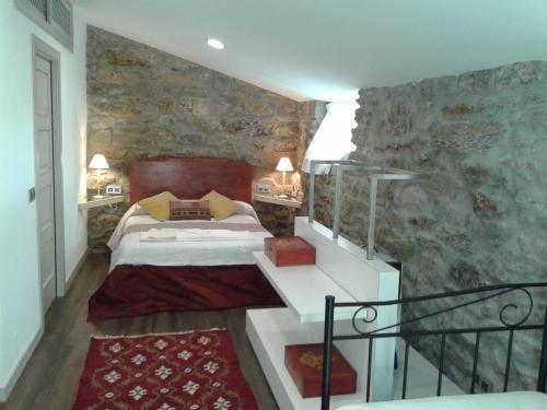 a bedroom with a bed and a stone wall at A casa de Mateu in Pontevedra