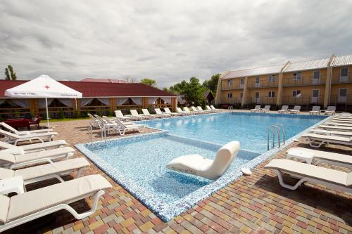 a large swimming pool with lounge chairs and a hotel at Райский Дворик in Pogreby