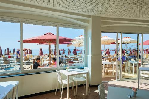 a restaurant with a view of the beach through the windows at Hotel Croce Di Malta in Imperia