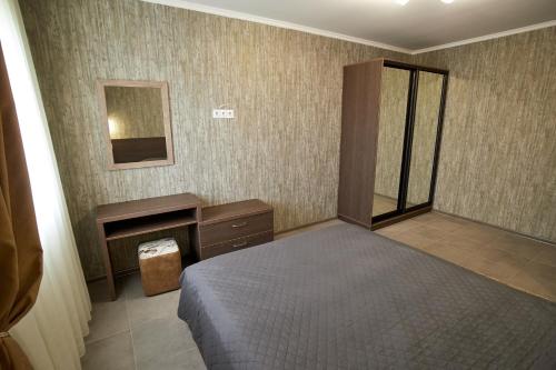 a bedroom with a bed and a desk and a mirror at Райский Дворик in Pogreby