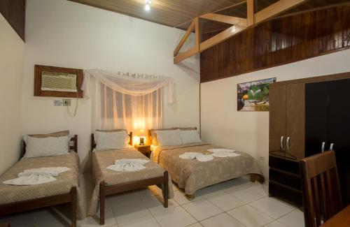 a hotel room with two beds and a window at Águas do Pantanal Inn Pousada in Miranda